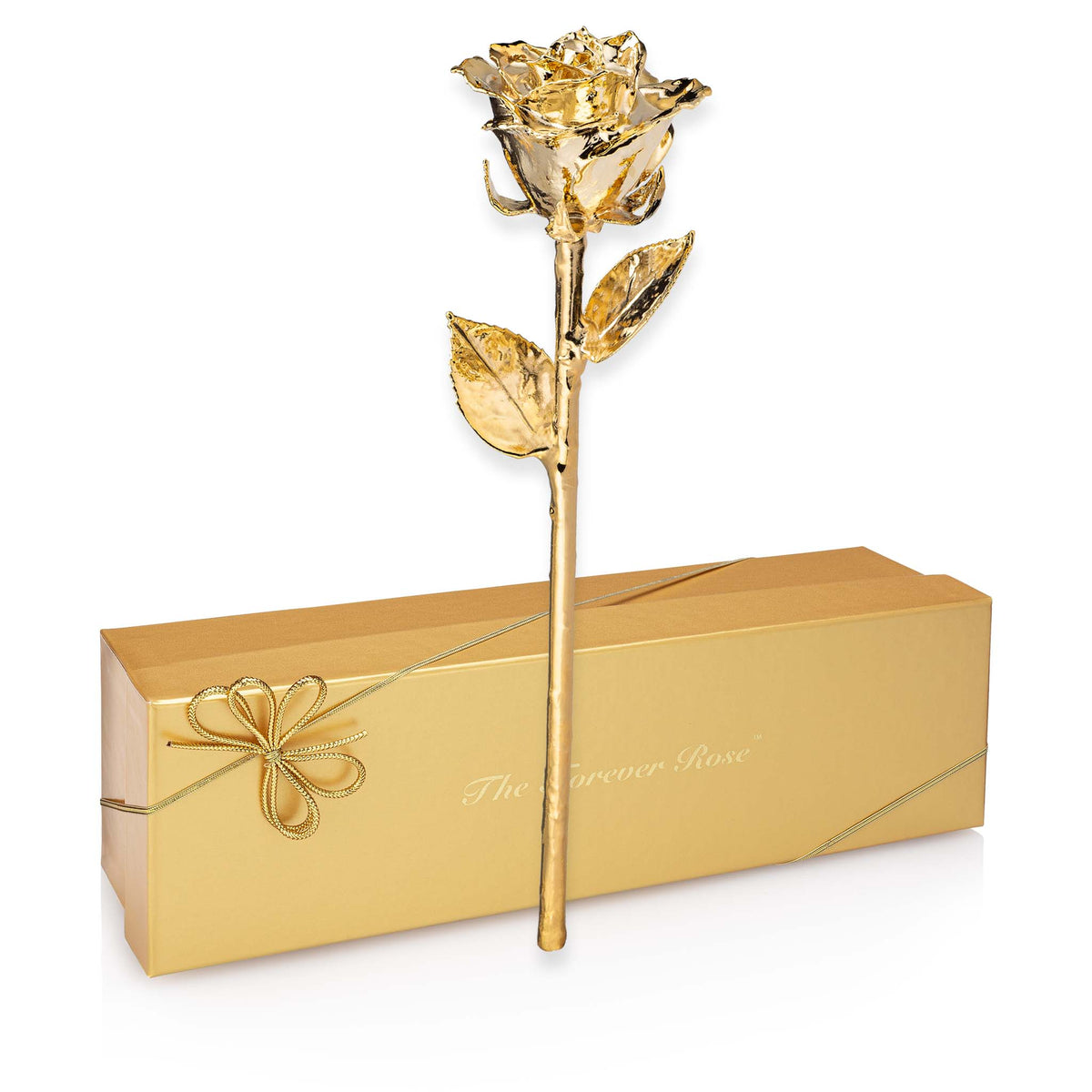 A single metallic gold artificial rose with a long stem and leaves stands upright in front of a gold gift box on a white background. The box has a bow and the words 'The Forever Rose' printed on it.
